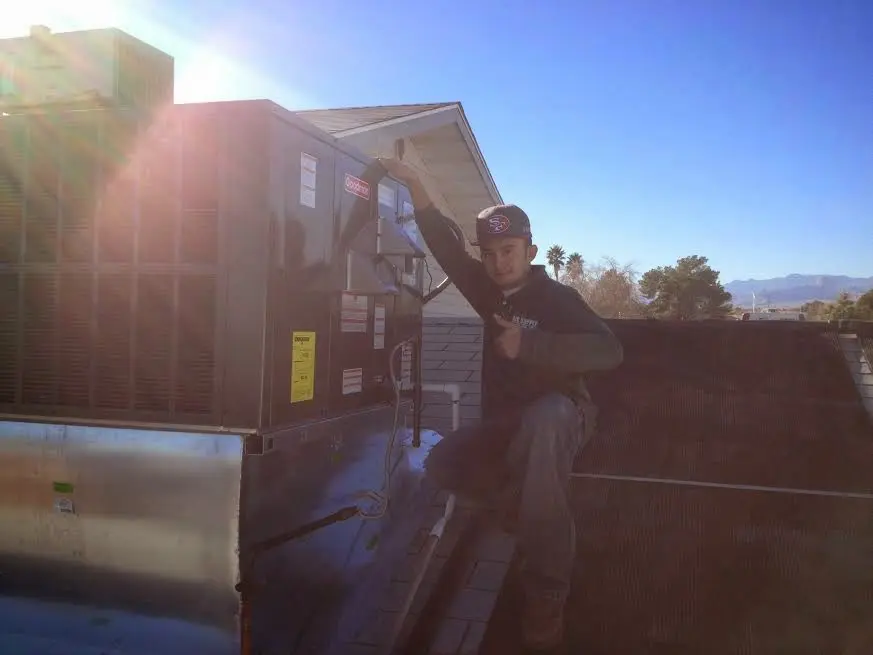 HVAC technician performing Air Duct Repair on a rooftop unit in Rochester